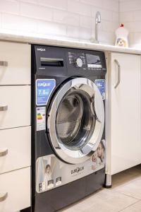 a washing machine is sitting under a counter at SkyView Luxe City View Apartment Saakadze Square in Tbilisi City