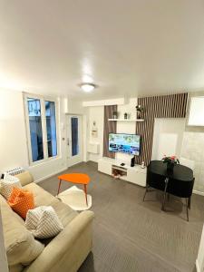 a living room with a couch and a flat screen tv at L'écrin d'Orphée in Bagnolet