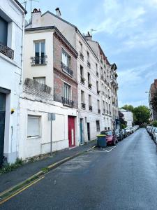 an empty street with buildings and cars parked on the side at L'écrin d'Orphée in Bagnolet