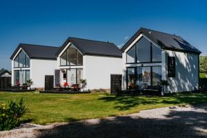 a house with black roof and windows on a lawn at My Slow Stay Łeba in Szczenurze