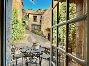 un patio con mesa y sillas fuera de una ventana en La Petite Maison- Fairytale Stay in Village Center, en Beynac-et-Cazenac 22 fotos más