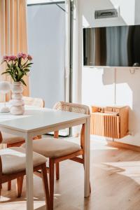 a white table with chairs and a vase with flowers at My Slow Stay Łeba in Szczenurze
