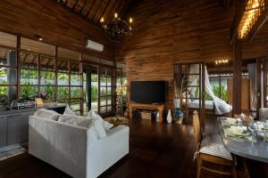 ウブドにある1BRV Cozy Villa with Amazing Rice Paddy Viewのソファ、テレビ、テーブルのあるリビングルーム