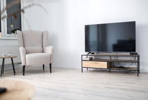 ein Wohnzimmer mit Fernseher und Sessel in der Unterkunft Stylish Poprad Stay - 10min to High Tatras & Parking in Poprad
