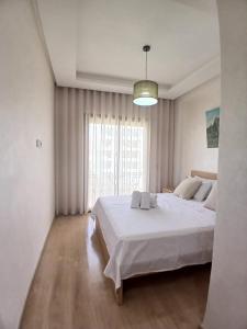 a white bedroom with a large bed and a window at Duplex Luxe 3 Chambres Vue Mer & Piscine à Zenata Eco City in Aïn Harrouda +30 photos