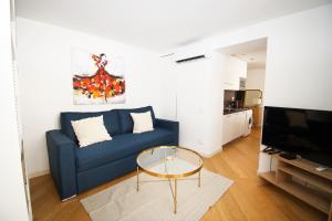 a living room with a blue couch and a glass table at Princes Victoria Standing Presta in Cannes