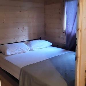 un letto con lenzuola e cuscini bianchi in una stanza di Chalet privé résident - camping la raviège a La Salvetat