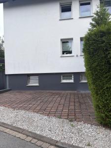 a white building with windows and a brick driveway at LV Apartment Externsteine in Horn-Bad Meinberg