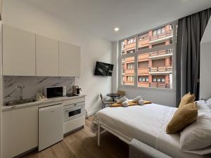 a bedroom with a bed and a kitchen with a window at Gabika Apartment 4 in Bilbao