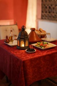 a table with a red table cloth with a plate of food at Auberge La Fibule Du Dades in Aït Idaïr