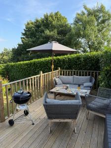 a patio with a table and a grill and an umbrella at Careful Cottage in Crediton