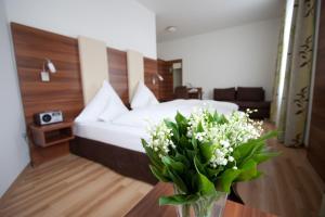 a bedroom with a bed with a vase of flowers on a table at Hotel am Viktualienmarkt in Munich