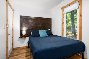 a bedroom with a bed with a blue comforter and a window at Arbutus Lake-King Suite-Pontoon Rentals in Traverse City