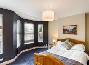 a bedroom with a large bed and windows at 4 Bedroom Belfast Townhouse in Belfast