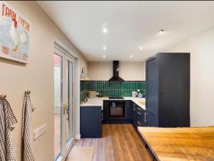 a kitchen with black cabinets and green tile at 4 Bedroom Belfast Townhouse in Belfast