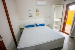 a bedroom with a white bed with blue pillows at Casa_Mare11 in São Miguel do Gostoso