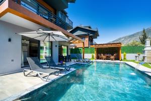 una piscina con sedie e ombrellone accanto a una casa di Villa TURK a Fethiye