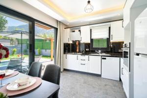 una cucina con mobili bianchi, tavolo e sedie di Villa TURK a Fethiye