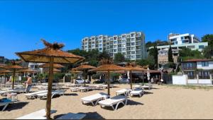 a beach with chairs and umbrellas and a building at Copacabacum Sea View in Varna City