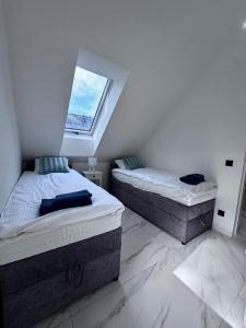 twee eenpersoonsbedden in een slaapkamer met een raam bij Marina Dziwnow Premium Haus in Dziwnów