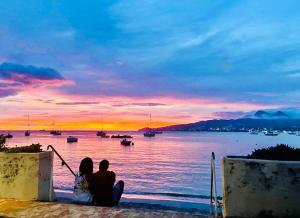 a couple sitting on a wall watching the sunset at Sous les Tropiques…Vue mer in Les Trois-Îlets