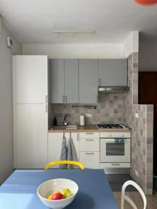 a kitchen with a bowl of fruit on a blue table at affascinante bilocale con piscina in Bordighera