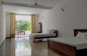 a bedroom with two beds and a large window at Mangroven River View Hotel in Bentota