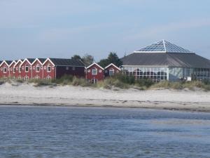una fila de casas rojas en la playa junto al agua en Feriecenter & Vandland Øster Hurup, en Øster Hurup