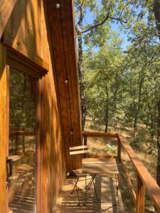 a wooden porch of a cabin with a bench on it at El Roble Glamping - Cabaña Alpina - Pet Friendly in Lagunilla