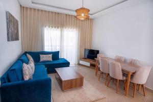 a living room with a blue couch and a table at La perle bleue de Beralmar Asilah in Oulad Akkou