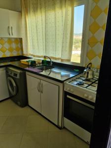a kitchen with a sink and a stove and a window at Résidence Somia Plage in Fnidek