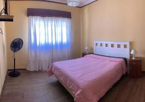 a bedroom with a bed with a pink bedspread and a window at chalet en alquiler la 15 in Miramar