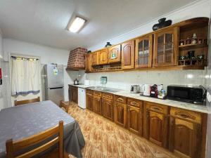 a kitchen with wooden cabinets and a table and a refrigerator at AL Sónia in Lagoa