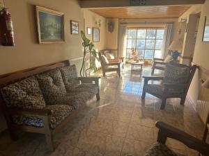 a living room with a couch and chairs and a table at Hostal Rio Ona in Ushuaia