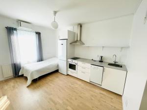 uma cozinha branca com uma pia e uma geladeira em Nya 1or 2or i centrala Halmstad em Halmstad
