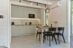 a kitchen with white cabinets and a table and chairs at Domki Premium Nautica blisko plaży in Rewal