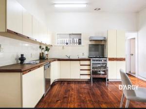 a kitchen with white cabinets and a wooden floor at Brisbane Rooms in Brisbane