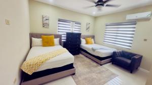 a bedroom with two beds and a chair in it at Modern Island Escape -Pool-Gym & Patio in Ocho Rios +13 photos