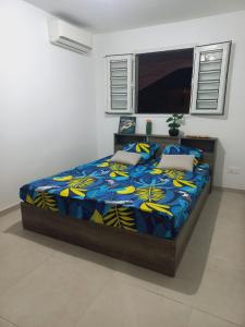 a bedroom with a bed with a blue and yellow bedspread at Flambroyant in Fort-de-France