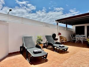 a patio with two chairs and a television on a roof at Villa Morriña by Vulcano Homes in Playa Honda