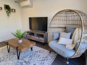 a living room with a wicker chair and a television at Entire Upper Level Suite - East Regina in Regina