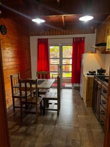 a kitchen with a wooden table and a kitchen with red curtains at Guazú Departamentos in Puerto Iguazú