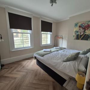 a bedroom with a large bed and two windows at Central Brighton, 2 bedrooms, sleeps 5 in Brighton & Hove