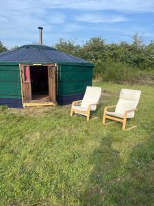two chairs sitting in front of a yurt at Escape to a cosy Yurt Retreat in Mickle Trafford +7 photos