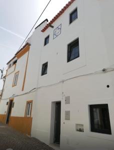 a white building with black windows on a street at Casa da Orada in Avis