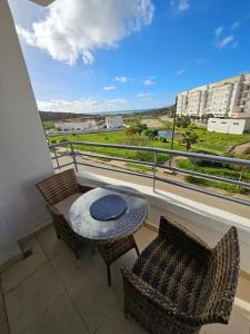 タンジェにあるMagnifique Appartement Vue sur Mer Tangerのバルコニー(テーブル、椅子付)、窓が備わります。