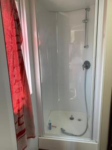 eine Dusche im Bad mit einem roten Duschvorhang in der Unterkunft Casa prefabricada in El Casar de Escalona