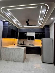 a kitchen with black cabinets and a stainless steel refrigerator at FIAA Hospitality 3BHK 2 FLATS in New Delhi