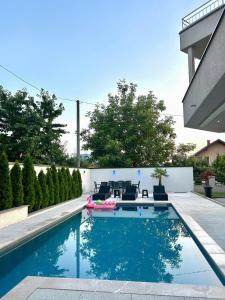 a swimming pool in a backyard with chairs at Villa Sunrise with swimming pool in Sarajevo