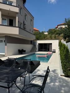 a swimming pool with chairs next to a building at Villa Sunrise with swimming pool in Sarajevo